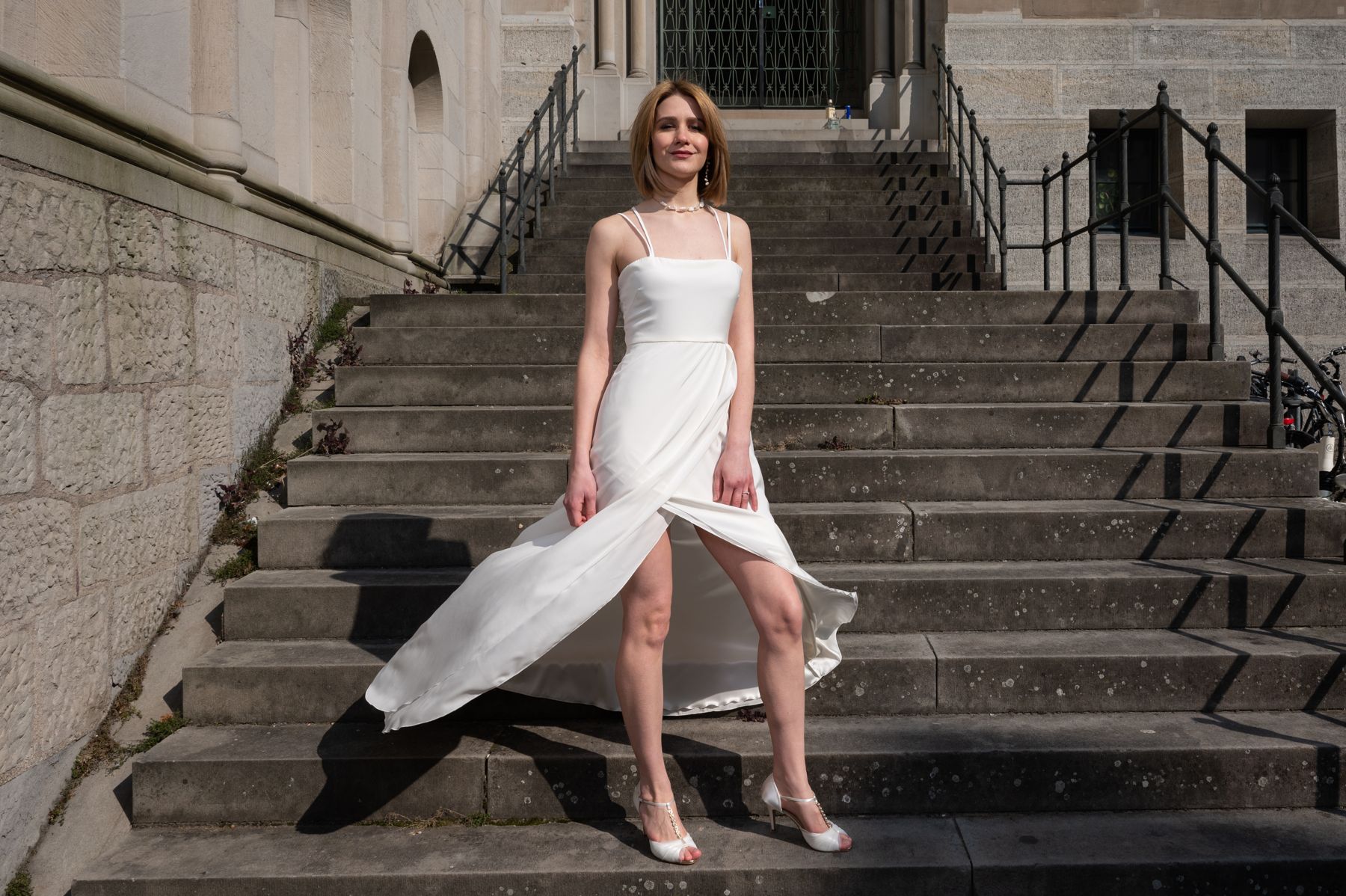 Hochzeitskleid nach Mass mit Beinschlitz auf einer Treppe in Zürich